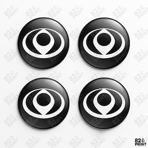 Peut inclure: Quatre boutons ronds noirs brillants, chacun orné d'un graphisme blanc. Le motif est une forme d'œil stylisée avec un cercle central et une flèche vers le bas. Le texte "820 PRINT" est répété autour des boutons.