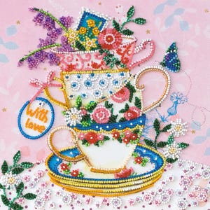May include: A beaded artwork featuring three stacked teacups adorned with floral patterns and a blue and white saucer. The cups are filled with beaded flowers and a butterfly. A tag with the words "With love" hangs from the bottom cup.