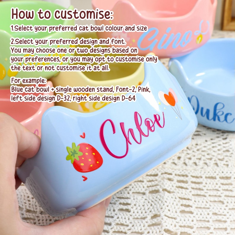 May include: A light blue ceramic cat bowl with the name "Chloe" in pink script, a strawberry graphic, and heart accents. The bowl is part of a customizable pet product line, with options for color, design, and font.
