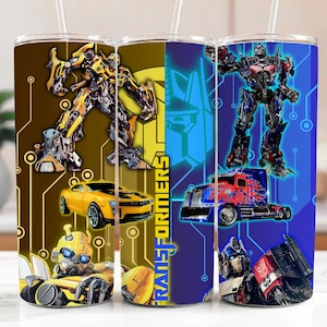 May include: Three stainless steel tumblers featuring Transformers characters. The designs include Bumblebee, Optimus Prime, and other Autobots and Decepticons. Each tumbler has a straw and a colorful design with a circuit board background.