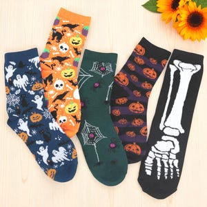 Puede incluir: Cinco pares de calcetines con temática de Halloween en varios colores. Los diseños incluyen fantasmas, calabazas, arañas y un pie de esqueleto. Los calcetines son de color naranja, azul marino, verde, negro y morado. Los calcetines están hechos de un material suave y cómodo.