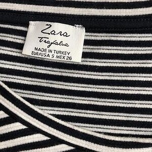 May include: Close-up of a black and white striped top. The top has a label that reads "Zara Trafaluc" and "Made in Turkey". The size is listed as EUR/USA S MEX 26. The fabric is a soft, knit material.