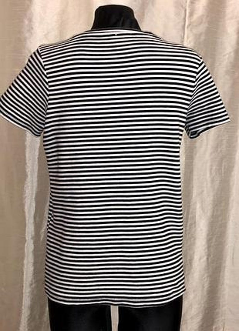 May include: A black and white striped t-shirt with short sleeves. The shirt is displayed on a mannequin. The stripes are horizontal and evenly spaced. The shirt is a classic nautical style.