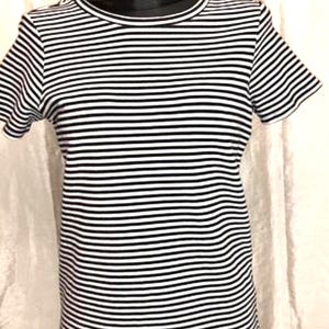 May include: A black and white striped t-shirt with short sleeves. The shirt is displayed on a black mannequin. The horizontal stripes are evenly spaced across the fabric. The neckline and sleeves are finished with a solid black trim.