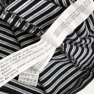 May include: Close-up of a black and white striped shirt. A white tag with text in multiple languages is attached to the shirt. The tag includes washing instructions and fabric composition.