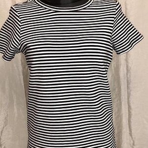May include: A black and white striped t-shirt with short sleeves. The shirt is displayed on a black mannequin. The stripes are horizontal and evenly spaced. The neckline and sleeves have a simple, clean finish.