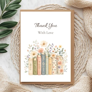 Puede incluir: Una tarjeta de felicitaci&oacute;n rectangular con fondo blanco que presenta el texto Thank You With Love en fuente negra cursiva y serif. Debajo del texto hay una ilustraci&oacute;n en acuarela de una fila de libros decorados con flores silvestres.