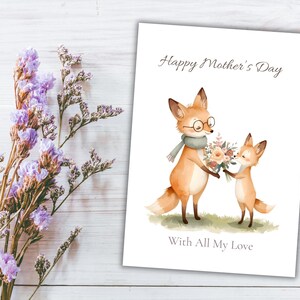 May include: A Mother's Day card featuring watercolor illustrations of two foxes. One fox wears glasses and a scarf, holding flowers. The card reads "Happy Mother's Day" and "With All My Love" on a white background.