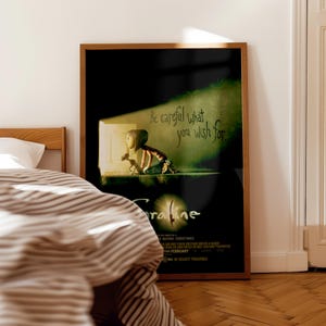 K&ouml;nnte beinhalten: Gerahmtes Filmplakat mit dem Text "Be careful what you wish for." Das Poster zeigt eine Illustration eines M&auml;dchens und eines Hundes in einer T&uuml;r, mit dem Filmtitel "Coraline" sichtbar. Dunkler Hintergrund.