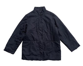 May include: A navy blue quilted jacket with a stand-up collar. The jacket has a button closure and long sleeves. The fabric appears to be lightweight and slightly textured. The jacket is designed for outerwear.