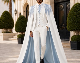 May include: A white suit featuring a matching cape with light blue floral embroidery on the shoulders. The ensemble includes a white vest with light blue buttons, a white dress shirt, a light blue tie, and white trousers with a light blue lining.