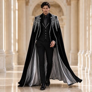May include: A black velvet floor-length cape featuring intricate silver embroidery on the shoulders, worn over a black vest, black dress shirt, and black trousers. The cape has a contrasting silver lining and white piping along the front edges.