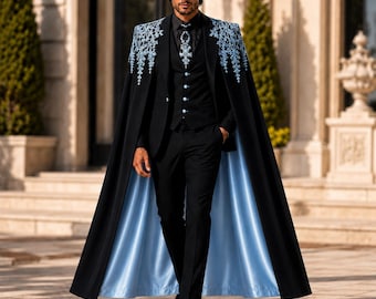 May include: A black suit comprising a waistcoat, trousers, and a long cape with a light blue lining. The cape shoulders and the necktie feature detailed light blue snowflake embroidery. The waistcoat includes light blue buttons matching the lining.