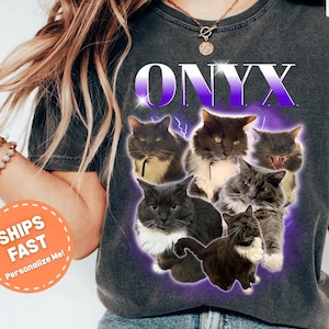 May include: A charcoal gray short-sleeve t-shirt featuring the word ONYX in a purple gradient font above a collage of six different cats. The cats are surrounded by a purple glowing aura with lightning bolt accents on a dark, washed-out fabric.