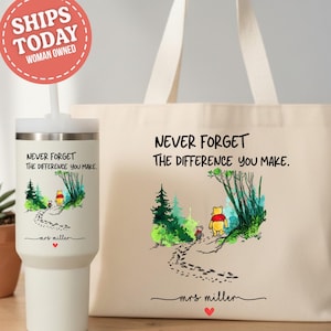 May include: A white tumbler and a beige tote bag with the text "NEVER FORGET THE DIFFERENCE YOU MAKE." Both items feature a watercolor illustration of Winnie the Pooh and Piglet walking on a path. The tumbler has a straw and the tote bag has long handles.