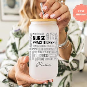 May include: A frosted glass tumbler with a bamboo lid and a stainless steel straw. The tumbler features the words "Nurse Practitioner" surrounded by related words. The name "Olivia" is printed at the bottom. A "Fast Shipping" sticker is visible.