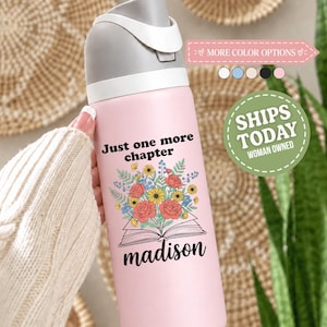 May include: A light pink water bottle with a gray lid and a white flip-top spout. The bottle features a graphic of an open book with a colorful floral bouquet emerging from the pages, along with the text Just one more chapter and madison.