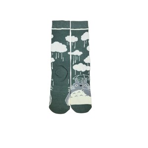May include: A pair of green socks featuring a cartoon character holding an umbrella under a rainy sky with white clouds. The socks are knee-high and made of a soft material.