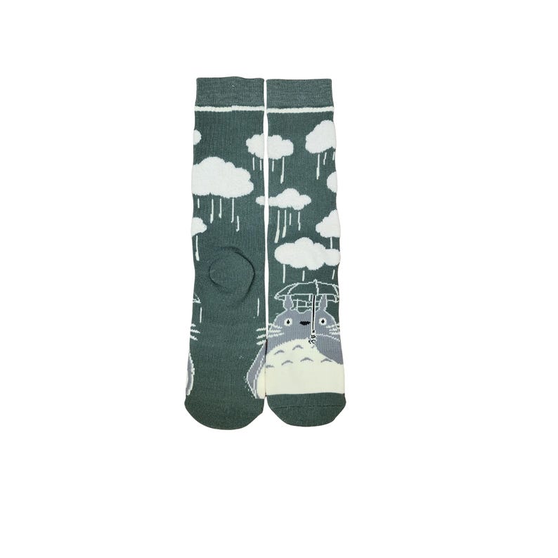 May include: A pair of green socks featuring a cartoon character holding an umbrella under a rainy sky with white clouds. The socks are knee-high and made of a soft material.