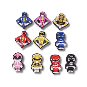 May include: A collection of ten colourful shoe charms featuring various Power Rangers characters in both standing and torso-only poses. The set includes figures in blue, pink, yellow, red, black, and white, each with distinct helmet and suit details.