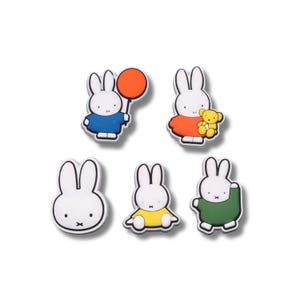 May include: A set of five white rabbit-shaped charms. One holds an orange balloon, one holds a yellow teddy bear, one is a head-only portrait, one is sitting in a yellow shirt, and one is standing in a green jumper. Each has black line details.