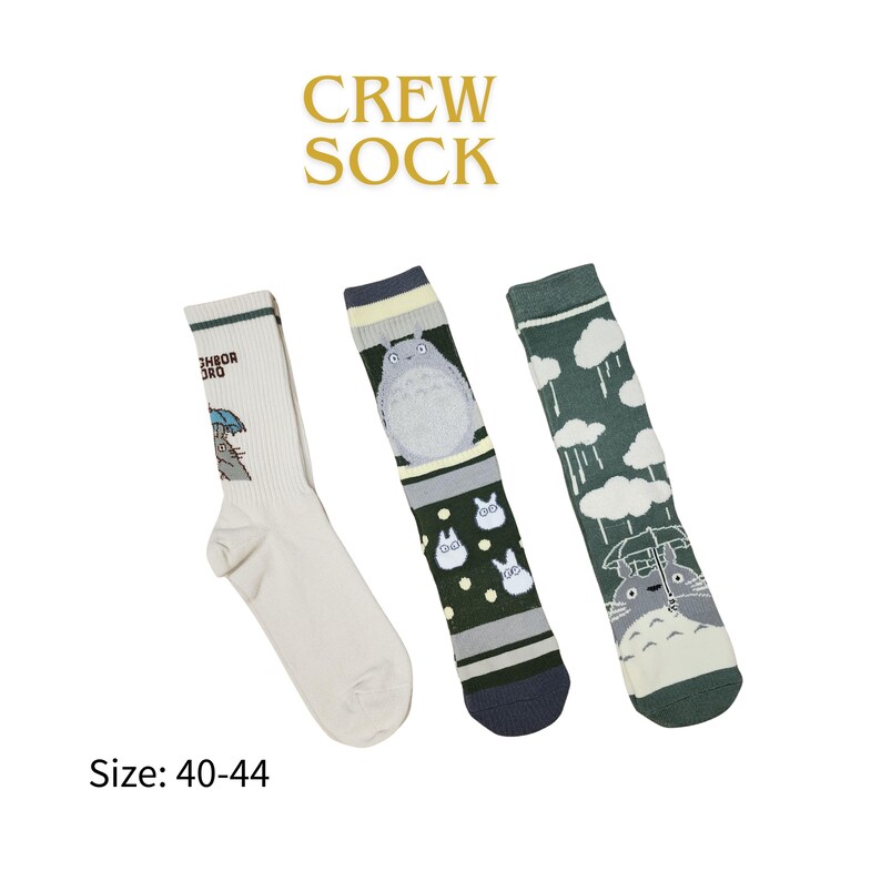 May include: Three crew socks with different designs. One sock is white with a cartoon character holding an umbrella. Another sock is green and gray with a cartoon character. The third sock is green with clouds and rain.