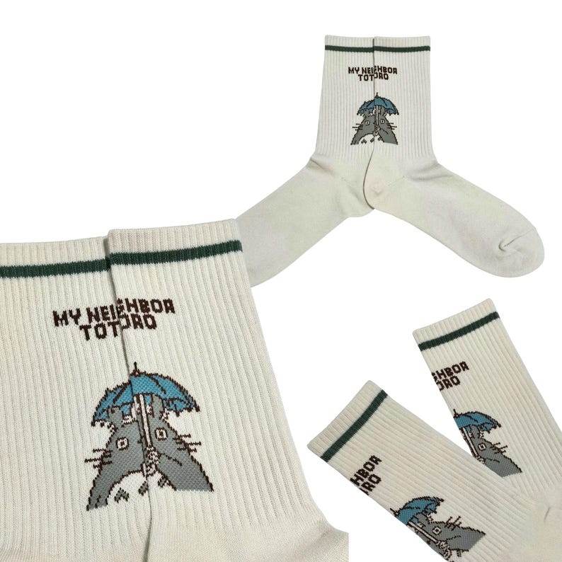 May include: Off-white socks with a green stripe at the top and the text "MY NEIGHBOR TOTORO". The socks feature a cartoon illustration of Totoro holding an umbrella. The socks are ribbed.