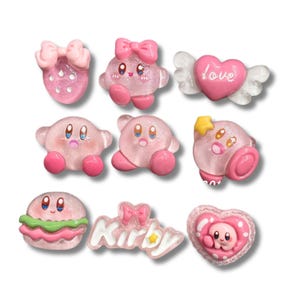 Könnte beinhalten: Eine Sammlung von neun kleinen, rosa, glitzernden Harzanhängern mit verschiedenen Motiven, darunter die Figur Kirby, eine Erdbeere mit Schleife, ein Herz mit Flügeln und dem Wort love, ein Hamburger sowie ein Schild mit dem Wort Kirby und einem Stern.