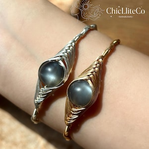 May include: Two wire-wrapped bracelets featuring round, grey, semi-translucent stones. One bracelet is crafted from silver-toned wire, while the other is made from gold-toned wire. The ChicLliteCo logo is visible in the upper right corner.