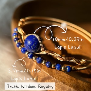 May include: Two gold-toned wire bracelets with Lapis Lazuli beads. One bracelet features a large 0.39-inch Lapis Lazuli stone, and the other has smaller 0.15-inch beads. The text reads "Truth, Wisdom, Royalty."