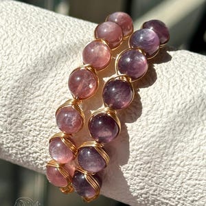 May include: Two wire-wrapped bracelets featuring round, polished beads in shades of pink and purple. The beads are secured with thin, metallic gold-coloured wire coils. The logo ChicLiteCo HandmadeJewelry is visible at the bottom of the image.