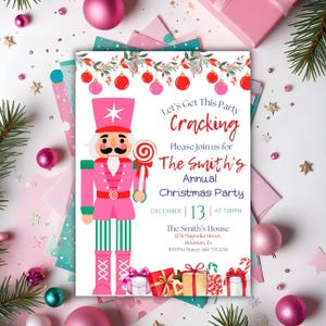 Könnte beinhalten: Rosa Weihnachtsparty-Einladung mit einem Nussknacker-Soldaten, der einen Lolli hält. Der Einladungstext lautet "Let's Get This Party Cracking" und enthält Datum, Uhrzeit und Adresse. Dekorative Elemente sind Ornamente und Geschenkverpackungen.