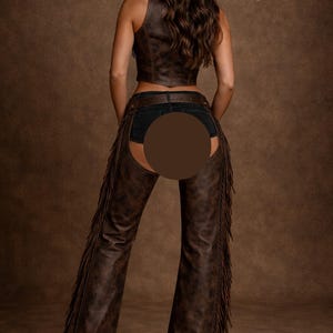 May include: A brown leather vest and chaps with fringe. The chaps have a flared leg design. The person is wearing a brown cowboy hat and denim shorts. The background is a solid brown color.