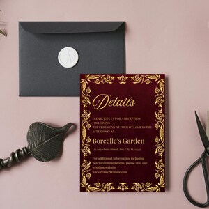 K&ouml;nnte beinhalten: Eine bordeauxfarbene Hochzeitseinladung mit goldenen floralen Akzenten und dem Wort "Details". Ein schwarzer Umschlag mit einem wei&szlig;en Wachssiegel, ein dekoratives blattf&ouml;rmiges Objekt und eine Schere sind ebenfalls vorhanden.