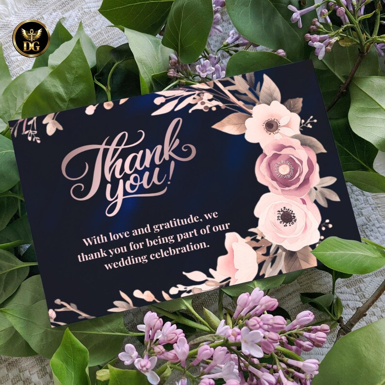 Op de afbeelding: Marineblauwe bedankkaart met ros&eacute;gouden belettering en bloemaccenten. De kaart luidt "Bedankt!" en bevat een boodschap van dankbaarheid voor een huwelijksfeest. De kaart is omgeven door groen en bloemen.
