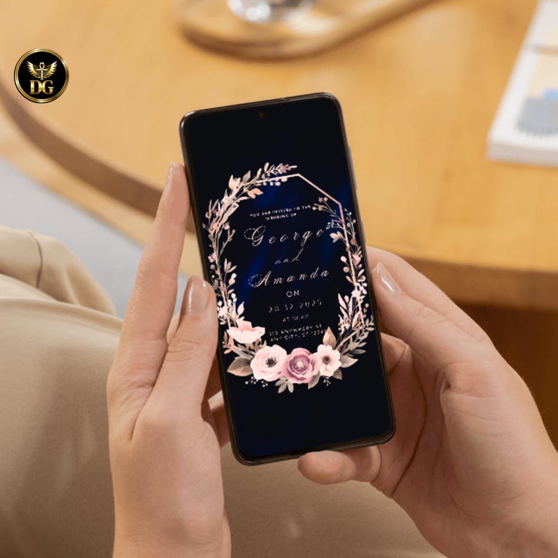 Op de afbeelding: Een smartphone toont een huwelijksuitnodiging met de namen "George en Amanda" in een elegant lettertype. De uitnodiging heeft een bloemenkransontwerp met roze en witte bloemen tegen een donkerblauwe achtergrond. De datum en het adres zijn ook zichtbaar.