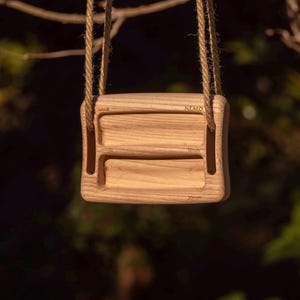 May include: A wooden climbing hold with rope handles. The hold is rectangular with rounded edges and features three recessed finger pockets labeled 8mm, 12mm, and 20mm. The word "NEMO" is engraved on the top.