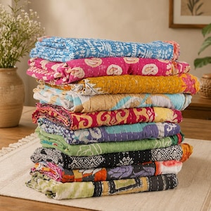 Può includere: Un'alta pila di trapunte in cotone piegate caratterizzate da vari colori vivaci e motivi complessi, tra cui blu, rosa, giallo, rosso, verde acqua, verde e nero, tutte rifinite con dettagli di impunture bianche visibili ovunque.
