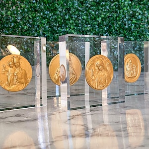 May include: Five gold-toned religious medallions displayed in clear acrylic frames. Each medallion features a different religious figure.