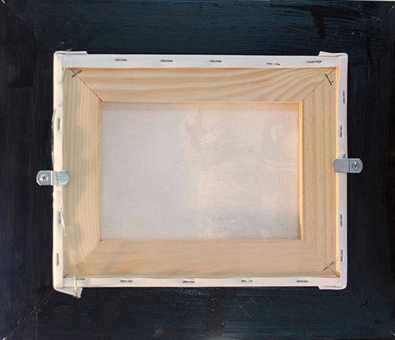 Puede incluir: La parte posterior de un cuadro de lienzo enmarcado con un marco de madera y un lienzo blanco. El marco tiene dos ganchos met&aacute;licos para colgar en los lados.