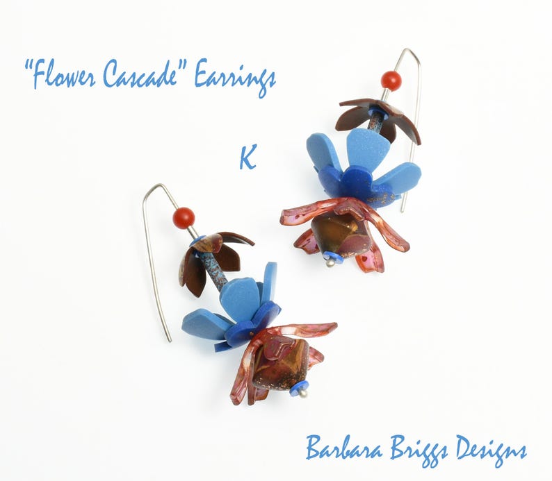 Op de afbeelding: Handgemaakte oorbellen met een bloemendesign. De oorbellen hebben blauwe, bruine en rode bloemvormige elementen, met een kleine rode kraal en een zilveren haak. De tekst "Flower Cascade" Earrings is zichtbaar.