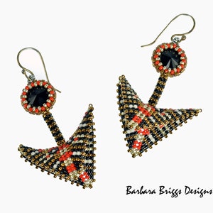 May include: A pair of black, white, and gold beaded earrings with red accents. The earrings are shaped like a pyramid with a black crystal at the top.