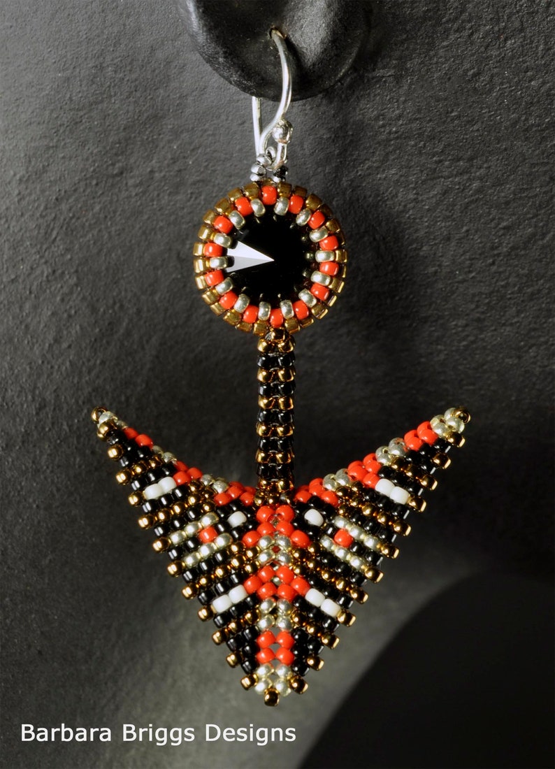 May include: Black, red, gold, and silver beaded earrings with a black crystal in the center. The earrings are shaped like an arrow.