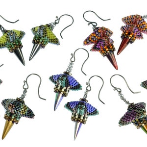 Puede incluir: Un conjunto de ocho pares de pendientes de cuentas. Cada par presenta una combinaci&oacute;n de colores &uacute;nica de cuentas iridiscentes, con un dise&ntilde;o puntiagudo en forma de cono. Los pendientes est&aacute;n hechos con ganchos de metal plateados.