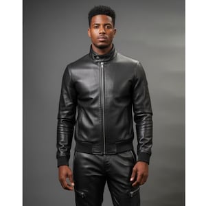 May include: A black leather jacket featuring a stand-up collar with a snap button closure, a full-length front zipper, and ribbed cuffs at the wrists. The jacket has a smooth finish and is paired with matching black leather trousers.