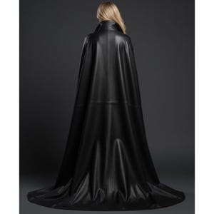May include: A long, black leather cape with a high collar and a flowing design. The cape is made of a smooth, shiny material and drapes to the floor. The back view shows the cape's full length and elegant silhouette.