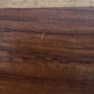 May include: A white ceramic mug with a black handle and the text "But First, Coffee" in a bold, black font. The mug is set against a blurred background, suggesting a cozy setting.