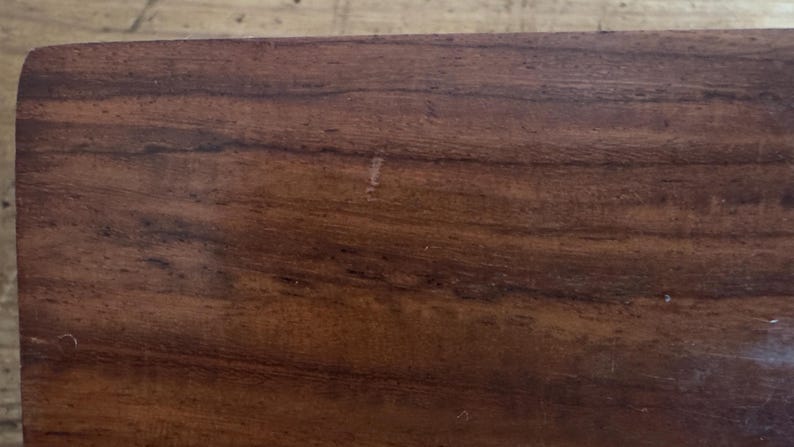 May include: A white ceramic mug with a black handle and the text "But First, Coffee" in a bold, black font. The mug is set against a blurred background, suggesting a cozy setting.