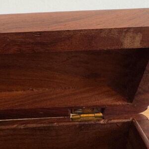 May include: A white ceramic mug with a black handle and the text "But First, Coffee" in a bold, black font. The mug is set against a blurred background, suggesting a cozy setting.