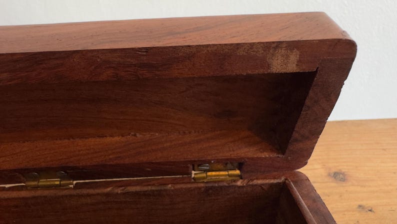 May include: A white ceramic mug with a black handle and the text "But First, Coffee" in a bold, black font. The mug is set against a blurred background, suggesting a cozy setting.